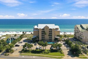 A beachfront hotel with a pool, parking, and a view of the beach and ocean.