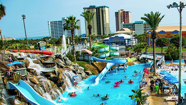 A water park with multiple water slides and pools, surrounded by palm trees and buildings. - ☀Private Pool~Across from Gulf~Carriage House~5BR Ocean Breezes🌅 (Destin)