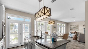 A modern kitchen with a central island, stainless steel appliances, and large windows. - ☀Private Pool~Across from Gulf~Carriage House~5BR Ocean Breezes🌅 (Destin)