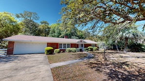 A single-story house with a garage, surrounded by trees and a well-maintained lawn.