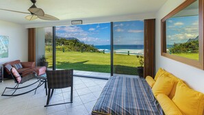 A room with a bed, a rocking chair, a sofa, and a view of the ocean. - PUU POA #110 GORGEOUS OCEAN VIEWS AIR CONDITIONED Condo! (Princeville)
