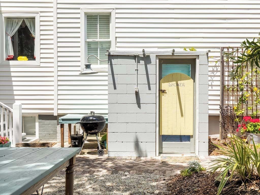 A house with a covered patio, a barbecue grill, and a door labeled "SHOWER".