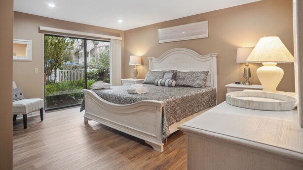 Un dormitorio con cama, lámparas de noche, una mesita y vistas al exterior.