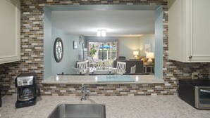 Una cocina con un espejo grande, cafetera, microondas y lavabo.
