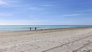 Una extensa playa de arena con cielo despejado y mar tranquilo.