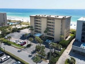 Un hôtel à plusieurs étages doté d’un parking, entouré de palmiers et offrant une vue sur la plage et l’océan.