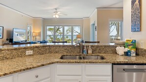 A kitchen with granite countertops, a stainless steel sink, and a ceiling fan. - 3 bedroom/3 bathroom Oceanfront Villa with Amazing Condo Complex Amenities (Hilton Head Island)