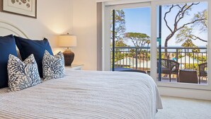 A bedroom with a large bed, a nightstand, a lamp, and a view of the outdoors through a sliding glass door. - 3 bedroom/3 bathroom Oceanfront Villa with Amazing Condo Complex Amenities (Hilton Head Island)