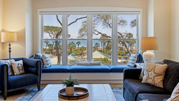 A living room with a large window, a sofa, a coffee table, and a lamp. - 3 bedroom/3 bathroom Oceanfront Villa with Amazing Condo Complex Amenities (Hilton Head Island)