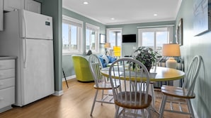 A modern kitchen with a refrigerator, dining table, chairs, and a view of the outdoors.