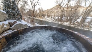 Ein Whirlpool, umgeben von schneebedeckten Felsen und einem Fluss.