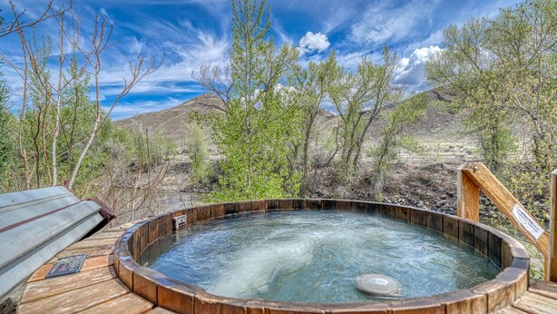 Ein Whirlpool, umgeben von einer Holzdielen-Terrasse, mit Blick auf Berge und spärliche Vegetation.