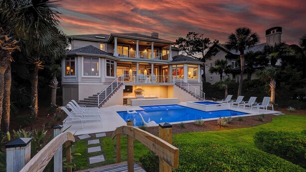 A two-story house with a swimming pool, a covered patio, and a well-maintained lawn.