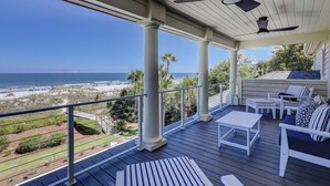 A covered outdoor deck with a view of the beach and ocean.