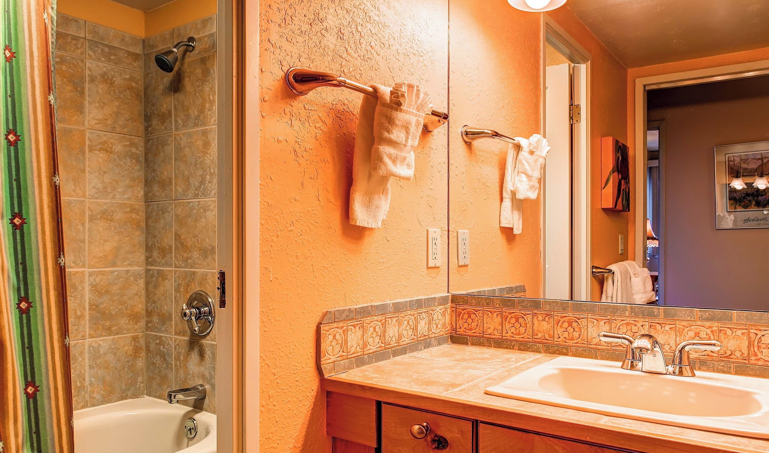 A bathroom with a shower, a sink, and a mirror.