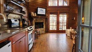 Una cucina accogliente con mobili in legno, un fornello e una macchina per il caffè. C'è un camino con una TV sopra che mostra 'Carolinamornings Luxury Vacation Rentals'.