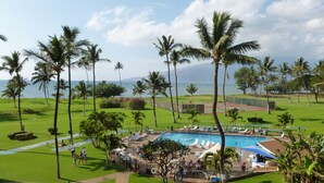 A pool area with lounge chairs and palm trees. - Maui Sunset Vacation Rentals B415 (Kihei)