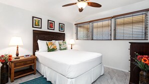A bedroom with a bed, two bedside tables with lamps, a wooden headboard, and a window with blinds. - 🏖️AC | Ocean View | Concierge Included (Kailua Kona)