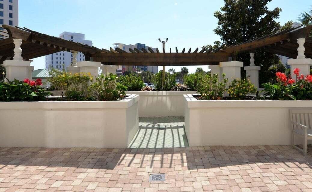 An outdoor garden area with a pergola, potted plants, and a bench.