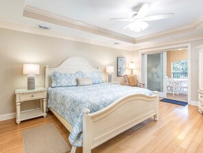 Ein Schlafzimmer mit einem großen Bett, zwei Nachttischen, einem Deckenventilator und Blick auf eine Terrasse.