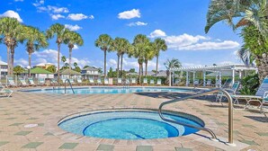 A swimming pool with lounge chairs, palm trees, and a clear sky. - Gulf View View,Beach Service, Maravilla 2303! (Miramar Beach)