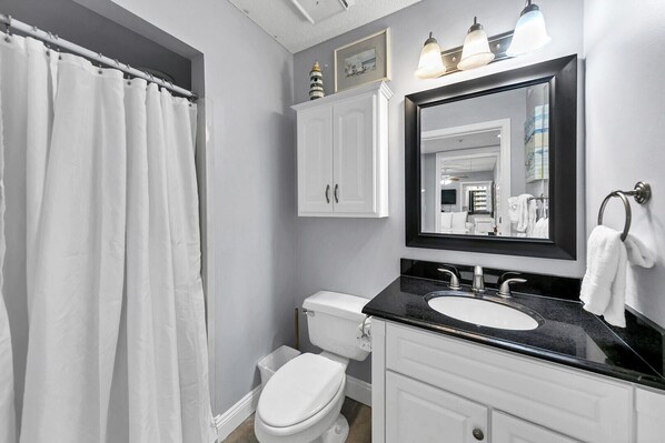 A bathroom with a white toilet, a black sink, and a large mirror.