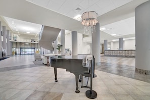 A spacious lobby with a grand piano, a chandelier, and a modern design.