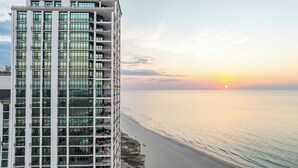 A high-rise building with multiple balconies overlooking a beach at sunset. - The Oasis At Orange Beach 2904 by Liquid Life (Orange Beach)
