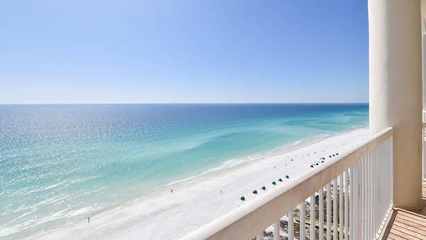 Blick auf einen Strand vom Balkon bei blauem Himmel.