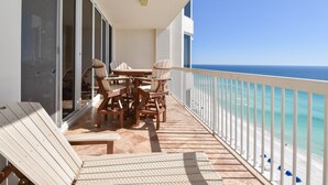 Ein Balkon mit Tisch und Stühlen mit Blick auf einen Strand.