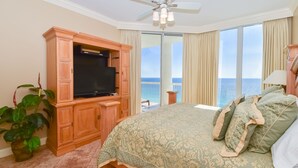 Ein Schlafzimmer mit einem großen Bett, einem Fernseher und einem Balkon mit Meerblick.