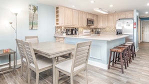 Une cuisine moderne avec des meubles de couleur bleu clair, un îlot central et un coin repas doté de chaises en bois.