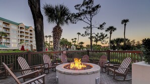An outdoor seating area with a fire pit surrounded by wooden chairs and a stone fire table. - Great 2 bedroom oceanfront Palmetto Dunes Villa! - Windsor Ct Amenities (Hilton Head Island)