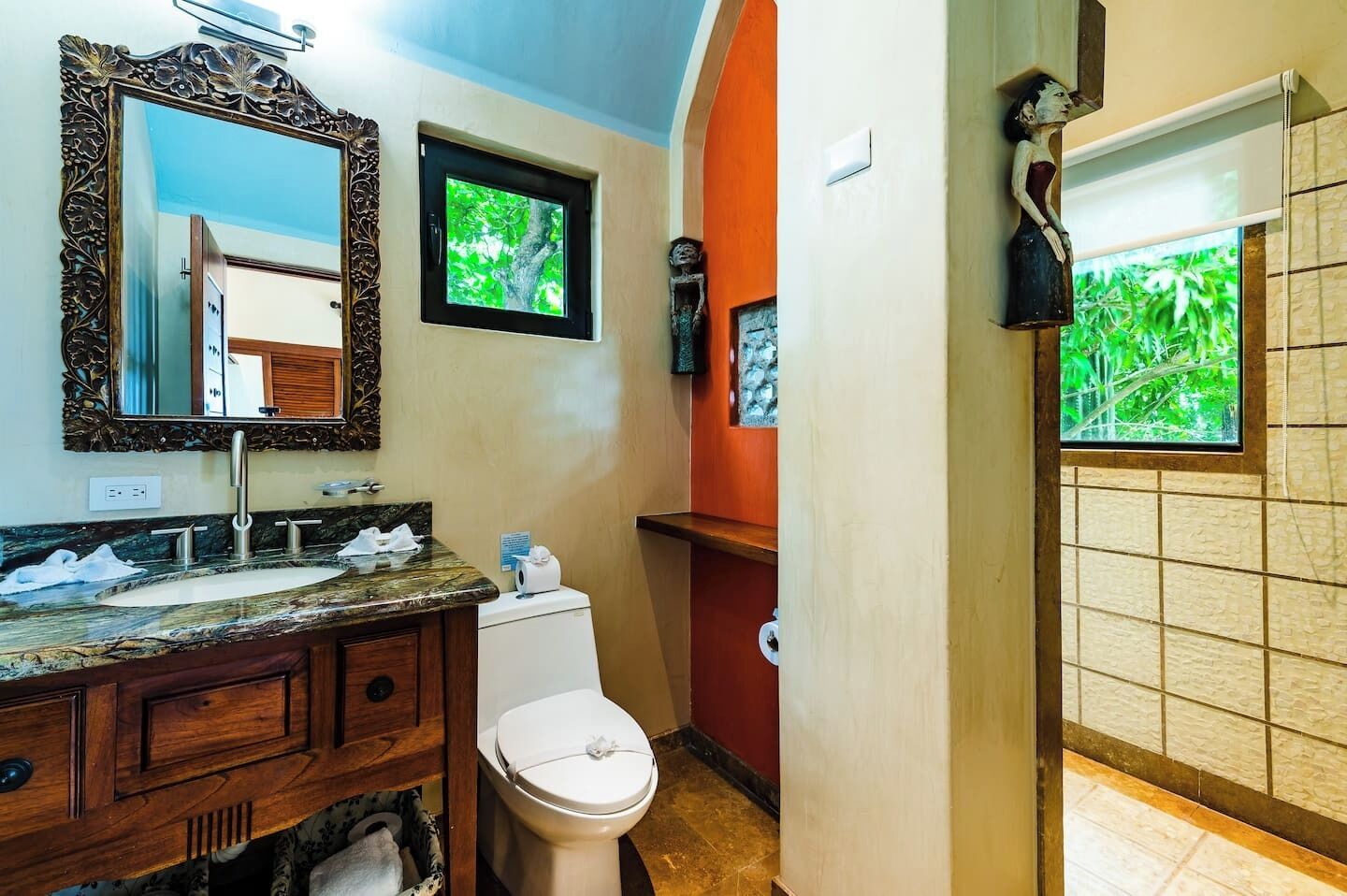 A bathroom with a marble sink, a toilet, a large mirror, and a shower area.