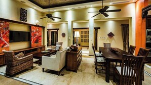 A spacious living room with a large flat-screen TV, comfortable seating, and a dining area with a wooden table and chairs. - Casa Pipilacha♛Impressive Ocean view♛ Infinity Edge Pool and ktcn (Tamarindo)