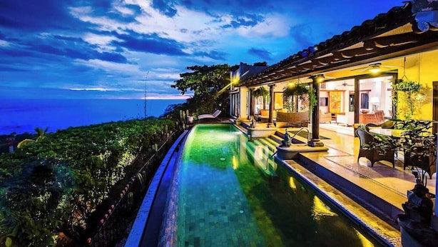 A poolside area with a view of the ocean, a covered patio, and a well-lit interior space. - Casa Pipilacha♛Impressive Ocean view♛ Infinity Edge Pool and ktcn (Tamarindo)