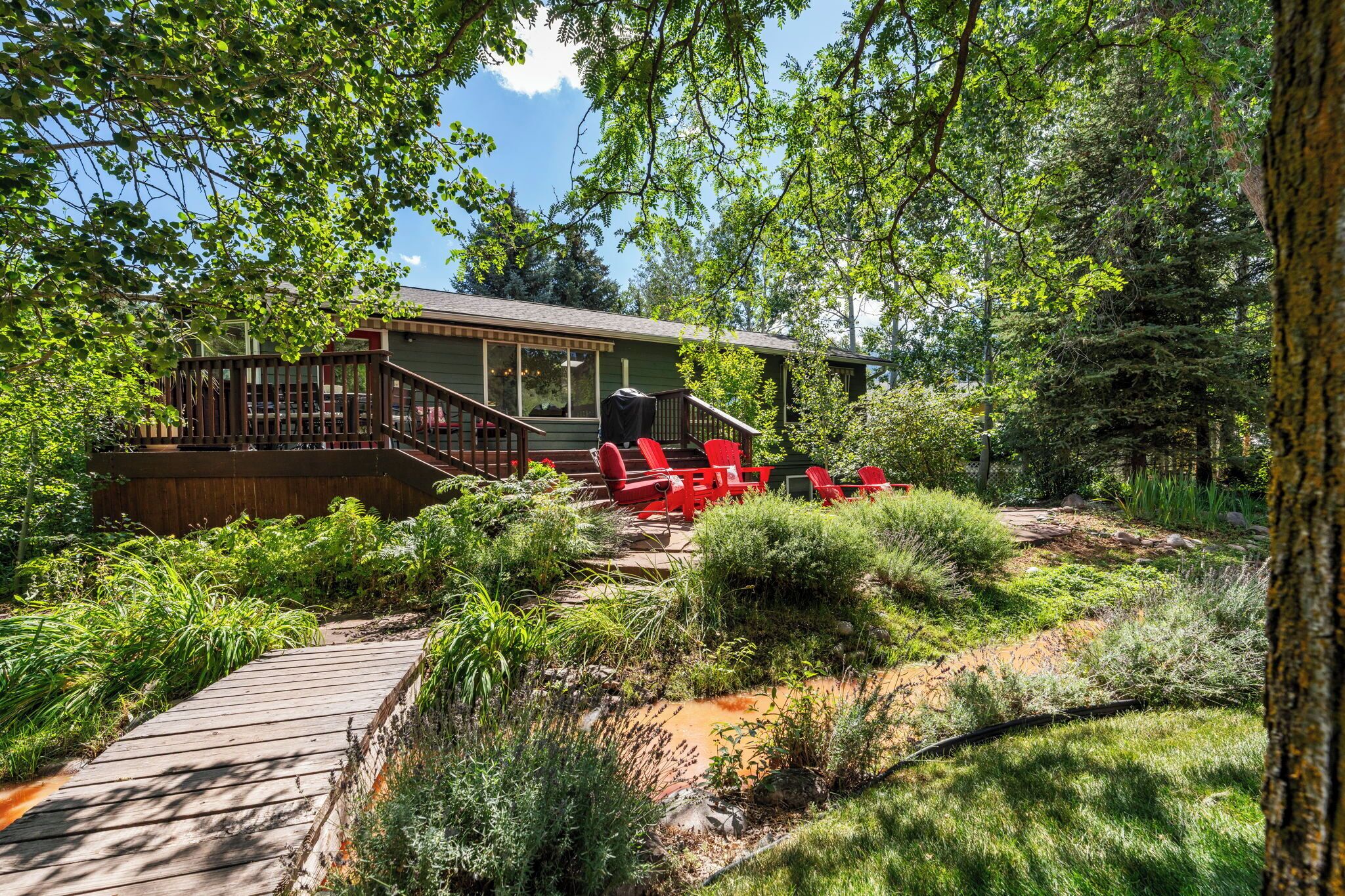 A wooden deck leading to a house with a covered outdoor seating area.