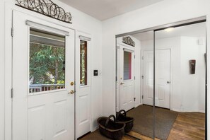 Un couloir avec des portes blanches, un miroir et un panier en osier.