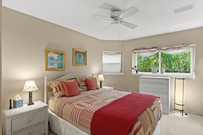 A bedroom with a bed, bedside tables, a ceiling fan, a window with a view of greenery, and two framed pictures on the wall. - Creekside Retreat with Yard, Close to Downtown and Ski, Dog Friendly (Durango)