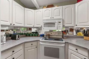 A kitchen with white cabinets, a microwave, a stove, and various appliances.