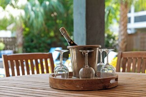 A wooden table with a metal container holding a bottle and several wine glasses. - Luxury Vaycay! Private Pool, Billiards, Hot Tub, Putting Green - 2602 Hartnett (Isle of Palms)