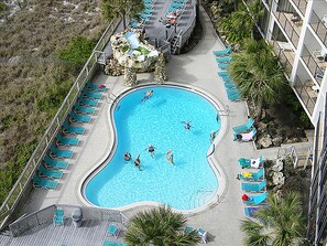 Ein großer, unregelmäßig geformter Pool, umgeben von Liegestühlen und einer Sonnenterrasse.