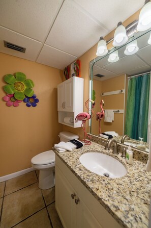 Ein Badezimmer mit Toilette, Waschbecken mit Spiegel und Duschvorhang.