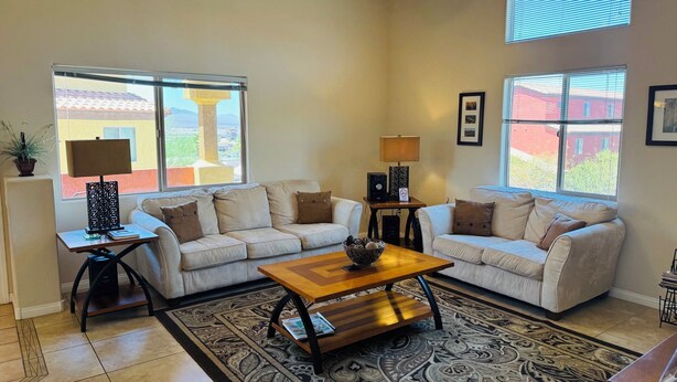 A living room with two sofas, a coffee table, a ceiling fan, and large windows with a view. - Wild Card by Mesquite Vacation Rentals: Pet Friendly with Community Amenities and $510 in free daily activities (Mesquite)