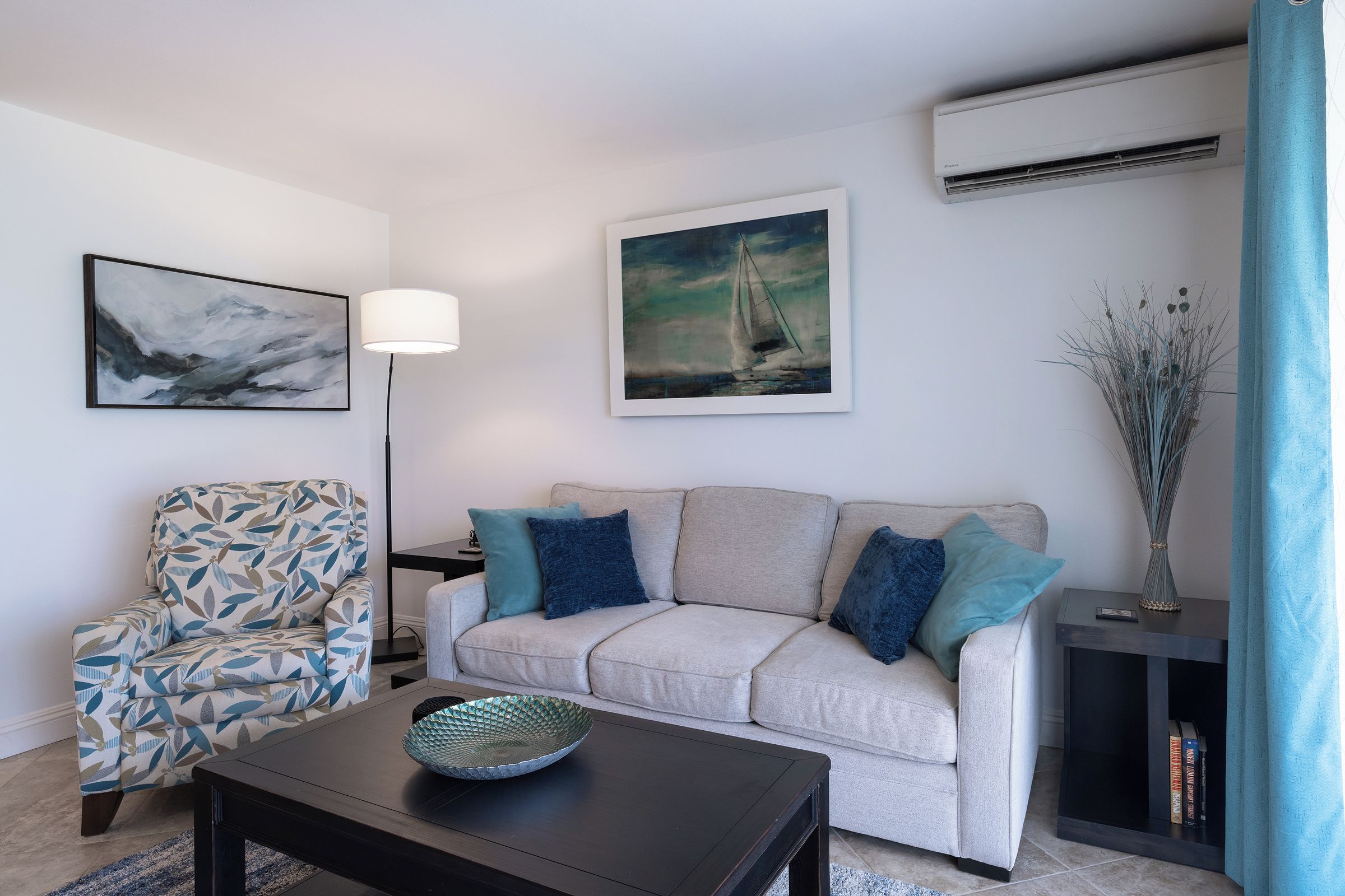 A living room with a sofa, a chair, a coffee table, and artwork on the walls.