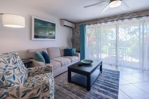 A living room with a sofa, a coffee table, and a painting on the wall.