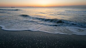 Une plage avec des vagues au coucher du soleil.