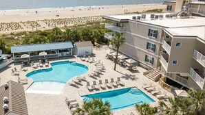 Un complexe hôtelier doté de deux piscines, offrant une vue sur la plage et comprenant un bâtiment avec des balcons.