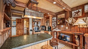 Una cocina rústica con vigas de madera, encimera de granito y taburetes de bar.