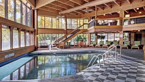 Un área de piscina interior de varios niveles con un interior de madera, múltiples zonas de estar y un cartel que indica 'NO DIVING'.